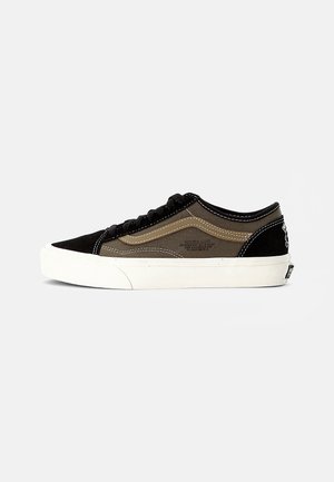 Niskie sneakersy z czarnym zamszowym noskiem i piętą, brązowymi materiałowymi bokami, białym falistym wzorem, czarnymi sznurówkami i grubą białą gumową podeszwą.