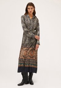 Rochie cu mâneci lungi și guler, realizată dintr-un material cu un model în tonuri întunecate, având talie strânsă și un tiv inferior cu modele contrastante.