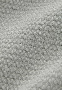 Tissu gris texturé avec un motif tricoté, présentant une surface douce, légèrement surélevée et une apparence uniforme sur l'ensemble du matériau.