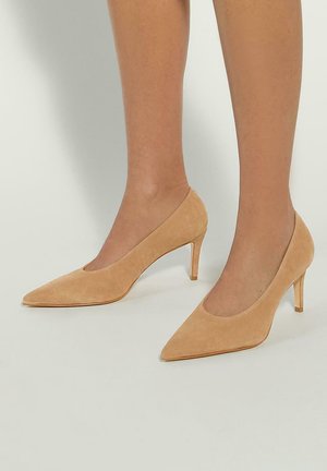 Beige suede high heels with a pointed toe, medium heel, and a cut-out design at the vamp. Smooth texture with minimalistic detailing.
