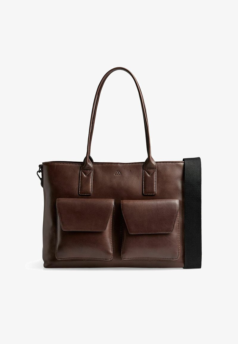 Sac fourre-tout en cuir marron foncé avec deux poches avant à rabat, double poignées et une bandoulière noire fixée sur le côté.
