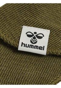 Tkanina w kolorze oliwkowym z teksturą i wzorem tkanym, z białą metką z czarnym logo i wyrazistym napisem "hummel".