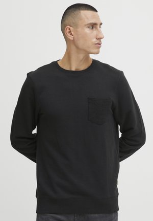 Black sweatshirt with long sleeves, a crew neck, and a textured patch pocket on the left chest. Soft fabric with ribbed cuffs and hem.
