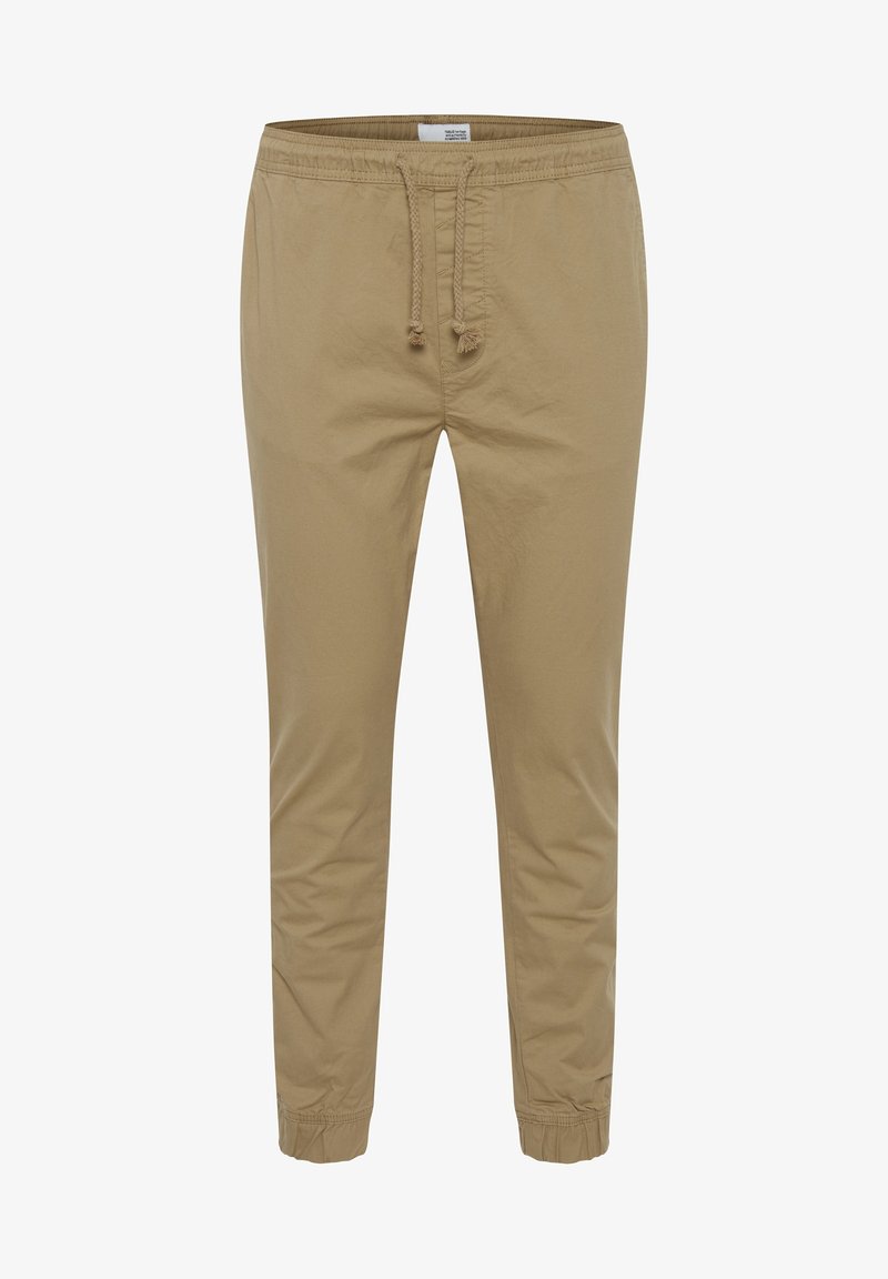Pantalon décontracté en coton beige avec taille élastique, cordons de serrage et bords élastiques aux chevilles.