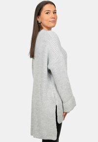 Maglione lavorato a maglia di un grigio chiaro con una vestibilità ampia, spacchi laterali e maniche lunghe. Presenta una texture a coste e un design oversize per il massimo comfort.