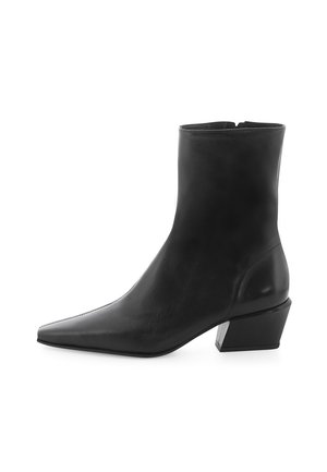 Bottine noire à bout pointu, fabriquée en cuir lisse. Présente un petit talon carré avec un accent métallique. Lignes épurées et design allongé.