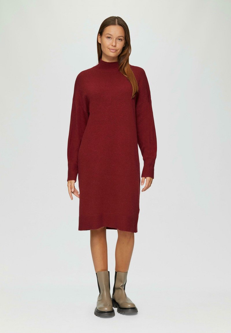 Bordeauxfarbendes Strickkleid mit langen Ärmeln, hohem Kragen und gerippten Bündchen und Saum, kombiniert mit beigen Knöchelstiefeln. Glatte Textur und lockere Passform.