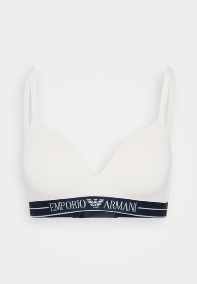 Soutien-gorge blanc avec un design en V, en matériau doux et à fines bretelles ; il présente une bande élastique bleu marine estampillée "Emporio Armani".