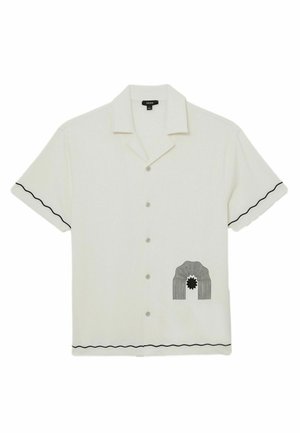 Weißes kurzärmeliges Hemd mit Knöpfen, schwarzen wellenförmigen Borten an Ärmeln und Saum sowie einem schwarzen abstrakten Bogen mit Sonnenmotiv auf der unteren Vorderseite.