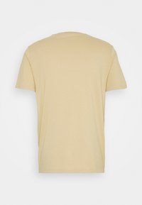 T-shirt beige à manches courtes et col rond vu de dos sur un fond blanc uni.