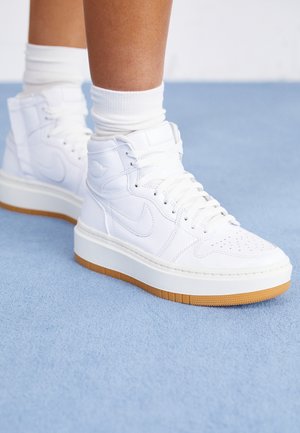 Zapatillas altas con parte superior de cuero blanco, puntera perforada y suela de goma. Cierre de cordones y acolchado en el collar para mayor soporte.