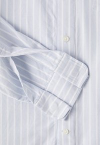 Light blue button-up shirt with vertical white stripes, plain collar, and button closure. Textured fabric with a smooth finish.