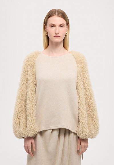 Beiger Pullover mit flauschigen, strukturierten Ärmeln und einem lässigen Schnitt. Glattes Körpergewebe kombiniert mit weichen, plüschigen Akzenten.