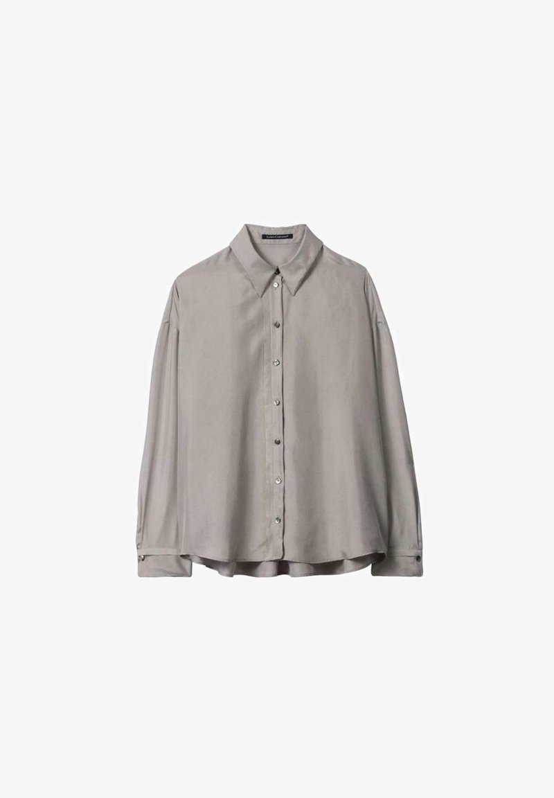 Chemise gris clair à manches longues avec col pointu et boutons sur le devant, posée à plat sur un fond blanc.