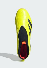 Zapato de fútbol sintético amarillo con un diseño sin costuras, acentos negros, una parte superior texturizada y un interior rojo con soporte acolchado.