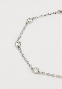 Collier en chaîne argentée mettant en avant des strass ronds et transparents intégrés dans des accents métalliques circulaires, régulièrement espacés le long de la chaîne.