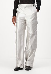 Silberne Cargo-Hosen mit Satinfinish, ausgestattet mit mehreren Seitentaschen, geradem Bein-Design und aufgerollten Säumen. Knopfverschluss an der Taille.