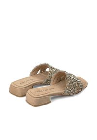 Beige slide-sandalen met een lage blokhak, voorzien van kruisschoenen versierd met multiculturele rhinestones en een zachte suède afwerking.