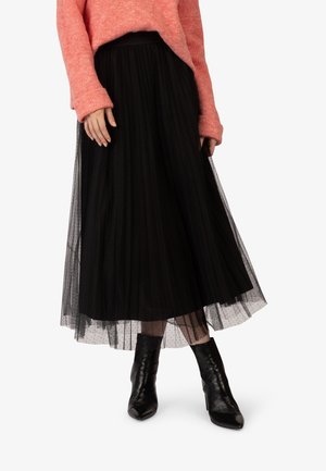 Black polka dot tulle midi skirt layered over a solid black lining, paired with a soft pink chunky sweater and black ankle boots.