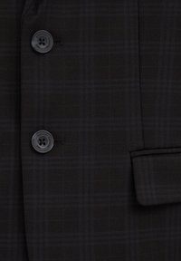 Černá kostkovaná látka na blejzr s jemným vzorem, obsahující dvě černé knoflíky a kapsu na levé straně. Hladká textura.