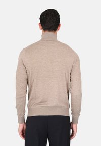 Maglione beige a collo alto con maniche lunghe, design aderente, polsini e orlo a coste, realizzato in morbido tessuto a maglia, mostrato da dietro.