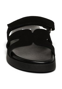 Sandalo nero con tomaia in suede, caratterizzato da ampie cinghie e una suola interna testurizzata. Chiusura regolabile con velcro e suola piatta in gomma.