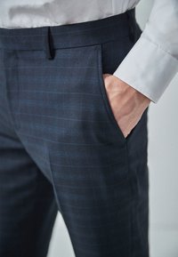 Námořnické kalhoty s jemným kostkovaným vzorem, vyrobené z hladké tkaniny, se bočními kapsami a slim fit střihem.