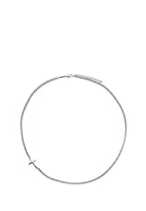 Sølvkjede med et lite, horisontalt sølvkorsanheng og en hummerlås med justerbare ledd på hvit bakgrunn.