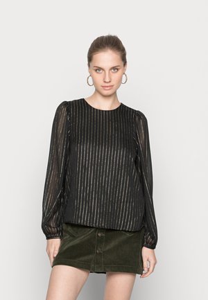 Top preto com mangas longas transparentes e riscas verticais douradas. Combinado com uma saia de veludo cotelê verde escura com fecho de botão frontal.