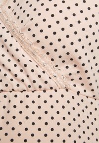 Jasnoróżowa tkanina w czarne kropki, z dekoracyjną koronką wzdłuż przekątnej szwy. Miękka tekstura, dopasowany krój.