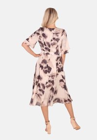 Florales Midikleid aus weichem Material mit einem hellbeigen Grundton und dunklen Blumenmustern. Verfügt über kurze Ärmel und eine taillierte Silhouette.