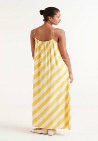 Vestido maxi a rayas amarillas y blancas con tirantes finos y una espalda recogida. Tela suave con una silueta fluida.