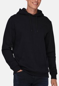 Sort hætte sweatshirt med lomme foran, justerbare snore og ribbede manchetter. Fremstillet af blødt stof med en glat tekstur.
