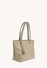 Sac fourre-tout beige avec surface texturée, anses fines et un gland décoratif. Présente une forme structurée et des bords contrastés.