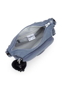 Pochette Kipling in morbido tessuto blu, con due scomparti con cerniera, un interno grigio e un ciondolo pompon nero attaccato alla cerniera.