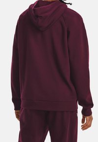 Felpa bordeaux con cappuccio regolabile e polsini a costine. Texture morbida e vestibilità rilassata, completata da pantaloni jogger abbinati.