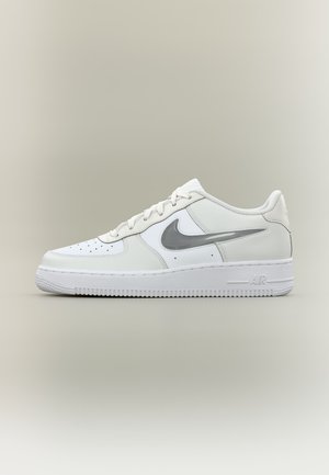 Baskets basses blanches avec un swoosh Nike gris clair, zone des orteils perforée, lacets blancs et semelle épaisse en caoutchouc sur fond neutre.