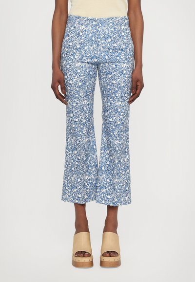 Pantalons évasés à imprimé floral bleu et blanc, fabriqués en tissu léger, avec une taille haute et une texture subtile. Coupe décontractée et détail à l'ourlet.