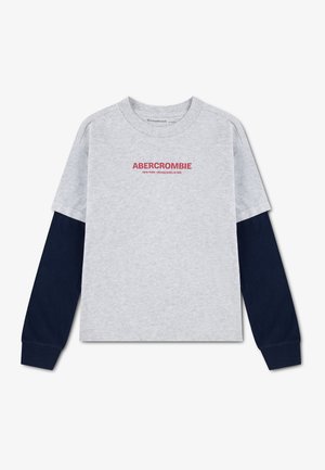 Lysegrå langærmet skjorte med marineblå ærmer og rød tekst "ABERCROMBIE" på brystet, lagt fladt på en hvid baggrund.