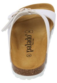 White sandals with a cork sole, featuring a textured brown insole and wide straps. The brand logo is printed on the insole.