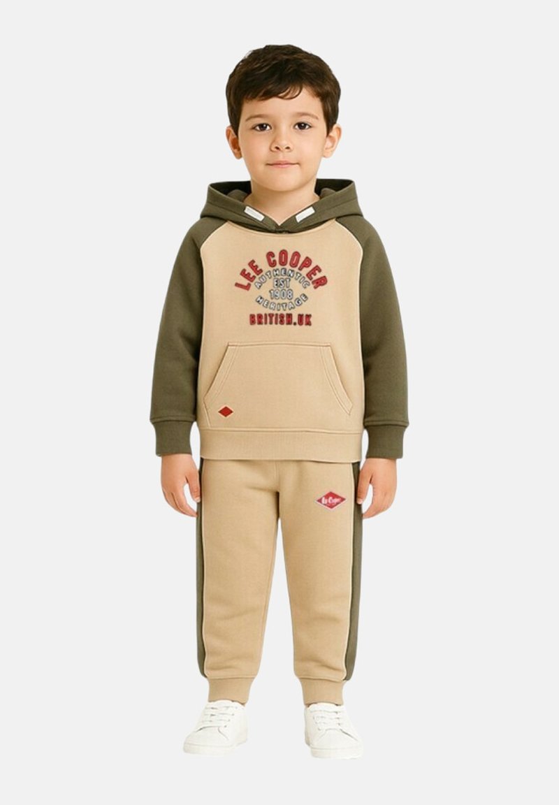 Sweat à capuche beige et vert olive avec une poche avant et un logo brodé. Pantalon de survêtement olive assorti avec un patch de logo rouge. Baskets blanches.