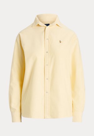 Chemise jaune clair à manches longues, boutonnée, avec col et petit logo brodé sur la poitrine gauche.