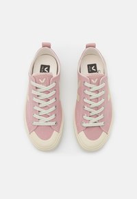 Baskets en toile rose avec un design à lacets, des accents beiges et une semelle en caoutchouc. Comprend une boucle à l'arrière pour un enfilage facile.