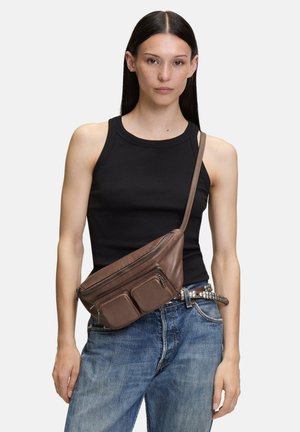 Brown leather fanny pack with multiple zippered pockets; flat design with a smooth texture; worn across the body over a black tank top.
