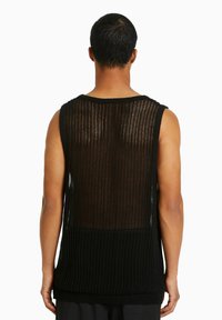 Black knit tank top with open weave, featuring a wide neckline and a longer back hem. The fabric texture is lightweight and breathable.