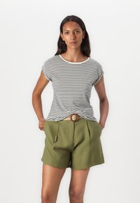 T-shirt rayé noir et blanc avec des manches retroussées, associé à un short taille haute vert et une ceinture tissée beige avec une boucle ronde.