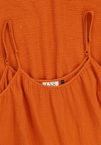 Oranje geweven top met dunne bandjes, textuurstof en geplooid ontwerp bij de halslijn. Etiket toont maat S/M.