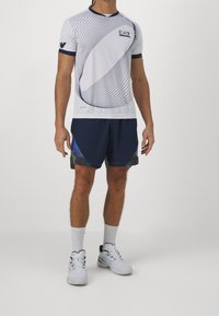 Bílý sportovní tričko s námořnickými pruhy a logem EA7 v kombinaci s námořnickými šortkami s barevnými akcenty a hladkým povrchem.