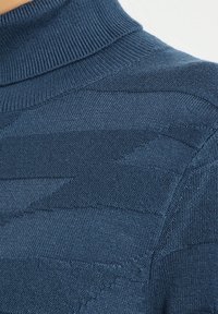 Pull à col roulé bleu marine avec un motif géométrique texturé ; fabriqué en tissu tricoté doux avec col et détails côtelés.