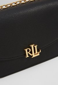 Czarna skórzana torebka o fakturowanej powierzchni, wyposażona w złoty łańcuchowy pasek i tłoczone logo RL na przedniej części.